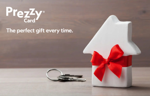 Housewarming gifts – a mini house with a red ribbon sitting next to keys